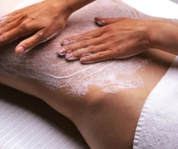 Behandlung im Frauenhotel Revital auf dem Balcon du Jura. Eine Frau liegt auf einer Massageliege und geniesst ein Rückenpeeling.