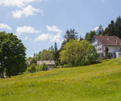Das Erholungshotel für Frauen, Revital, auf dem Balcon du Jura aus einiger Entfernung durch eine grüne Wiese fotografiert.