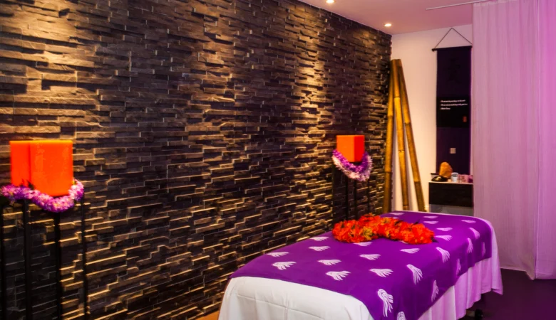 Behandlungsliege mit einer violetten Decke vor einer Steinwand im Frauenhotel Revital auf dem Balcon du Jura.